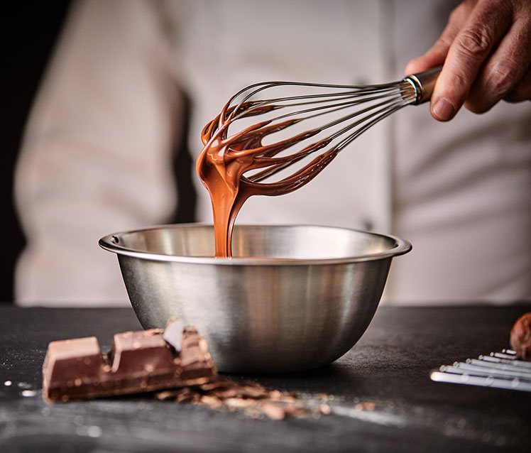 A chocolatier whisking a chocolate ganache